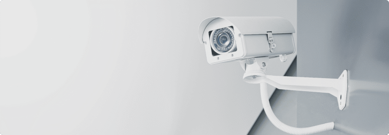 Caméra de vidéosurveillance blanche fixée au mur illustrant la sûreté des locaux professionnels