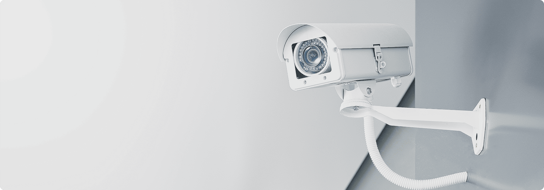 Caméra de vidéosurveillance blanche fixée au mur illustrant la sûreté des locaux professionnels